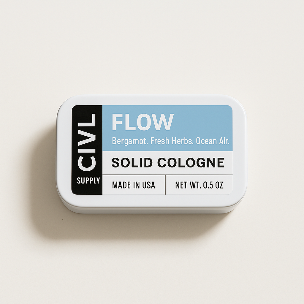 A small, rectangular tin container labeled 'FLOW Solid Cologne' with the text 'Bergamot. Fresh Herbs.